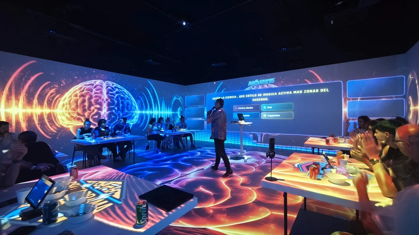 Presentador de Hit Show y equipos en una sala con proyecciones de ondas de colores